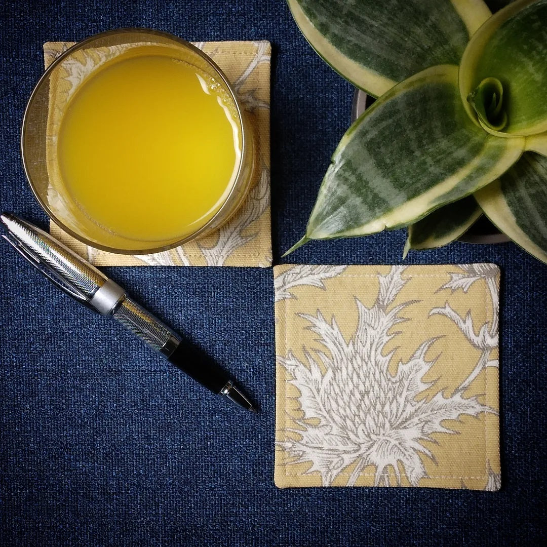 Square coasters with white thistle design on yellow background