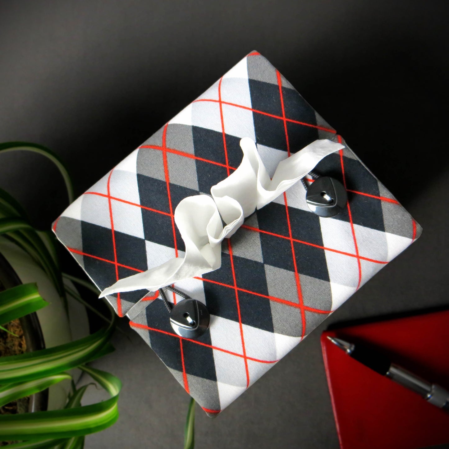 Square tissue box cover with black, grey, and red argyle pattern