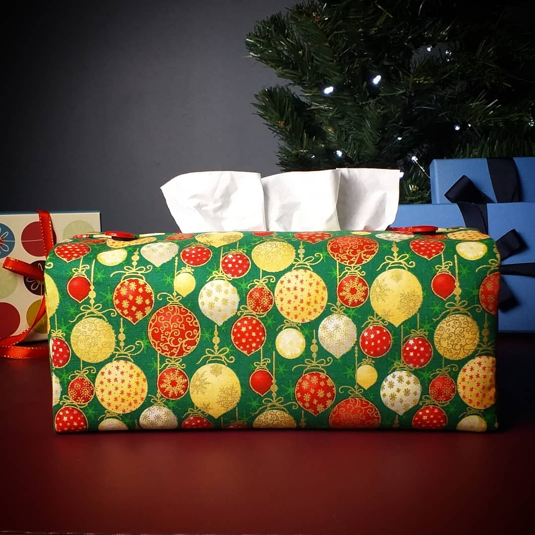 Cotton rectangle tissue box cover with holiday themed red, gold, and white Christmas baubles with metallic gold accent on green background