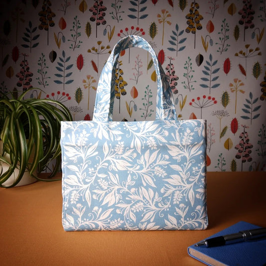 Mini tote bag with white wildflower silhouette design on light blue background