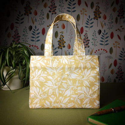 Mini tote bag with white wildflower silhouette design on yellow background