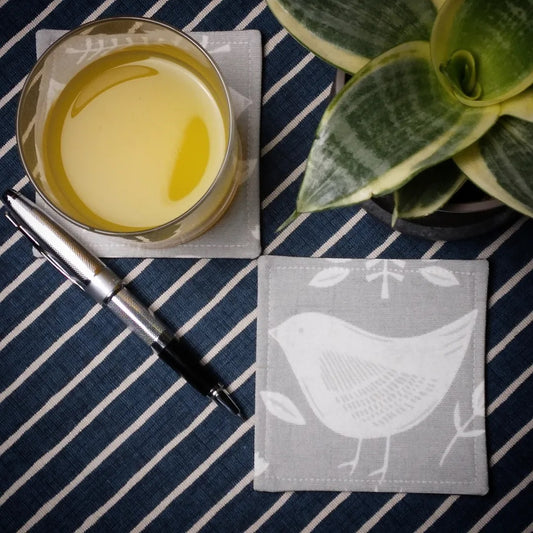 Square coasters with white bird design on grey background
