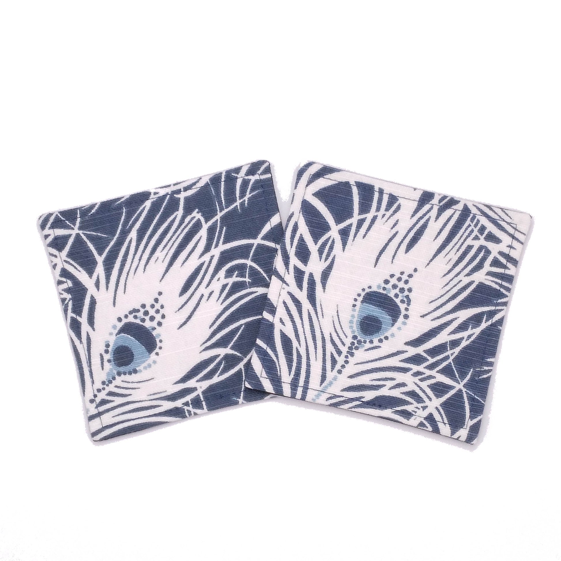 Square coasters with white peacock feathers design on blue background