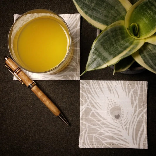 Square coasters with white peacock feathers design on natural colour background