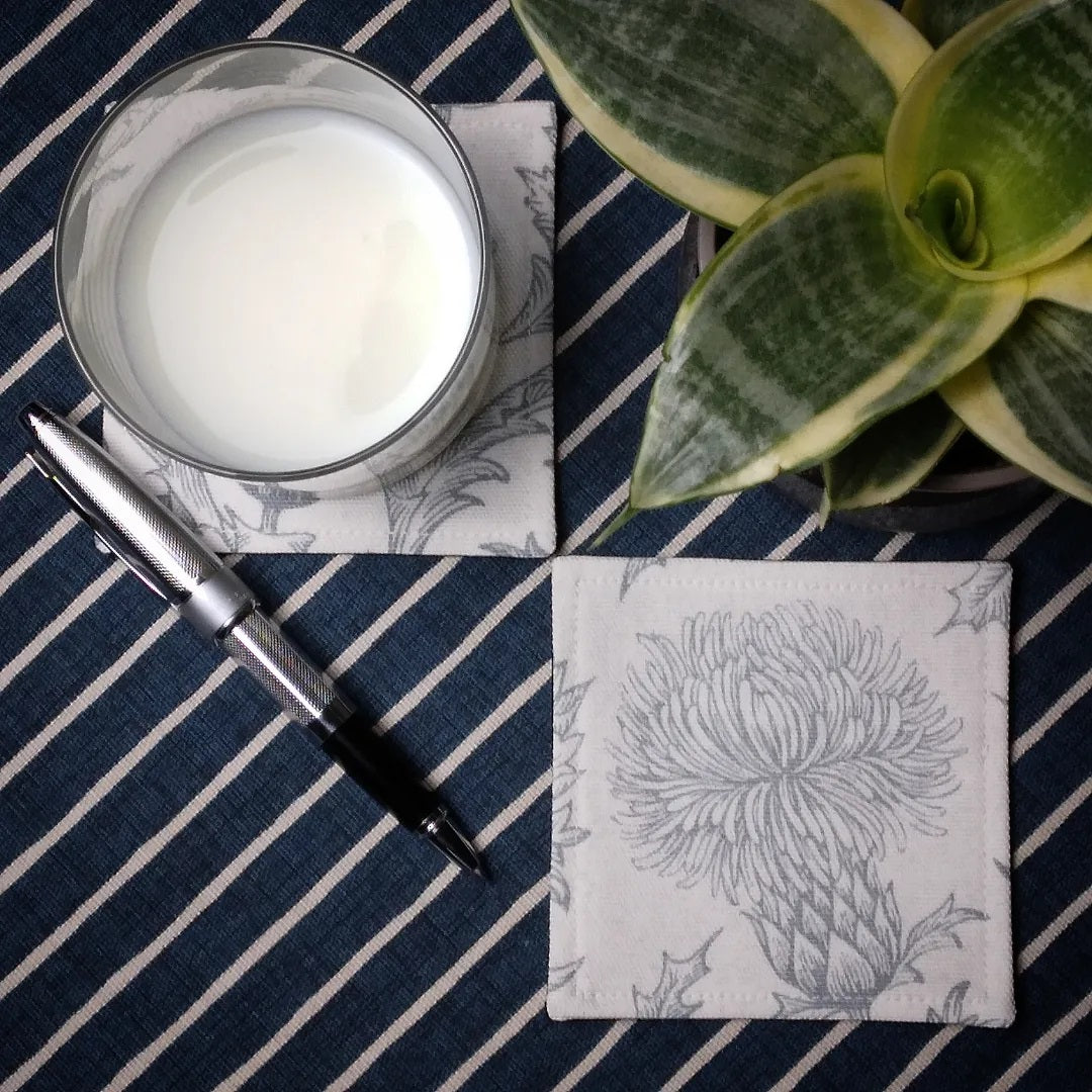 Square coasters with grey thistle design on white background