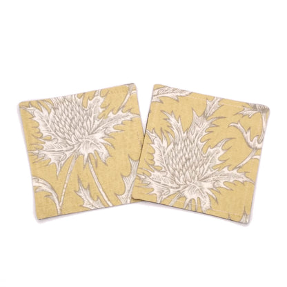 Square coasters with white thistle design on yellow background