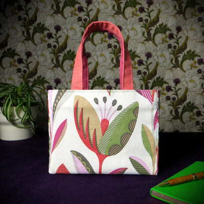 Small cotton tote bag with shades of moss green, raspberry pink, soft grey, and rhubarb red tulips on off-white background