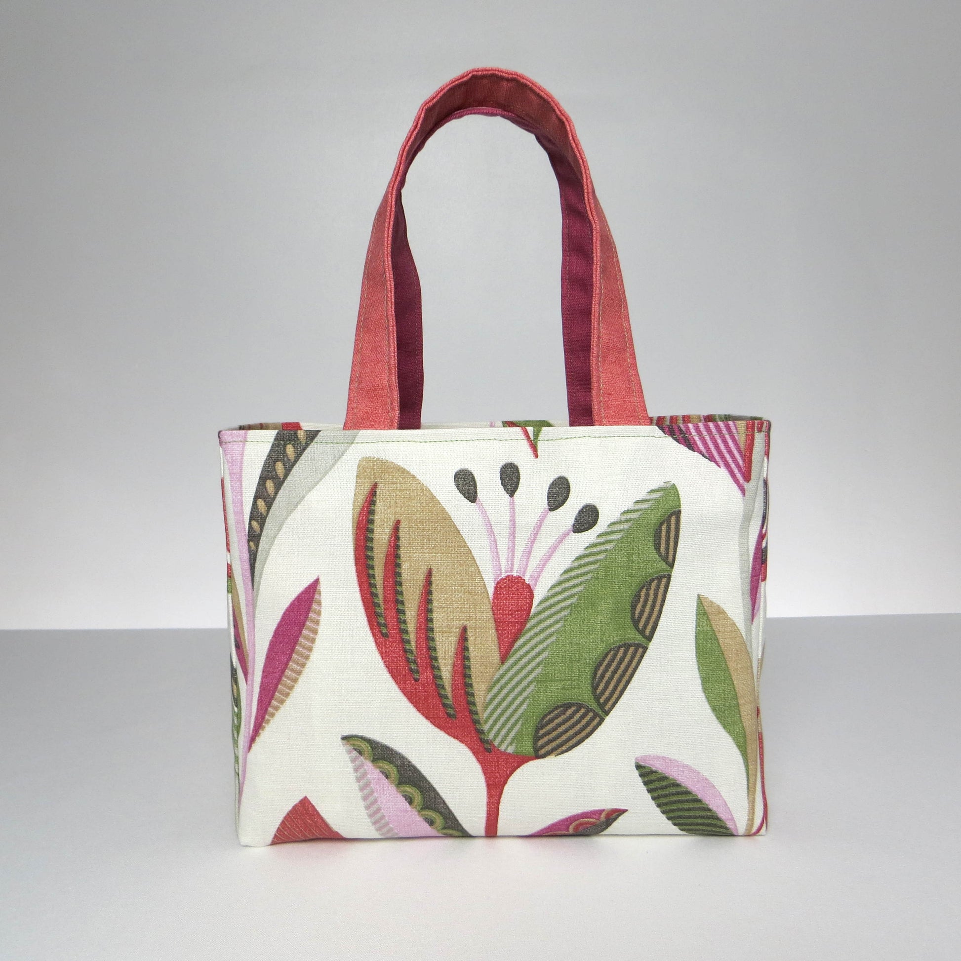 Small cotton tote bag with shades of moss green, raspberry pink, soft grey, and rhubarb red tulips on off-white background