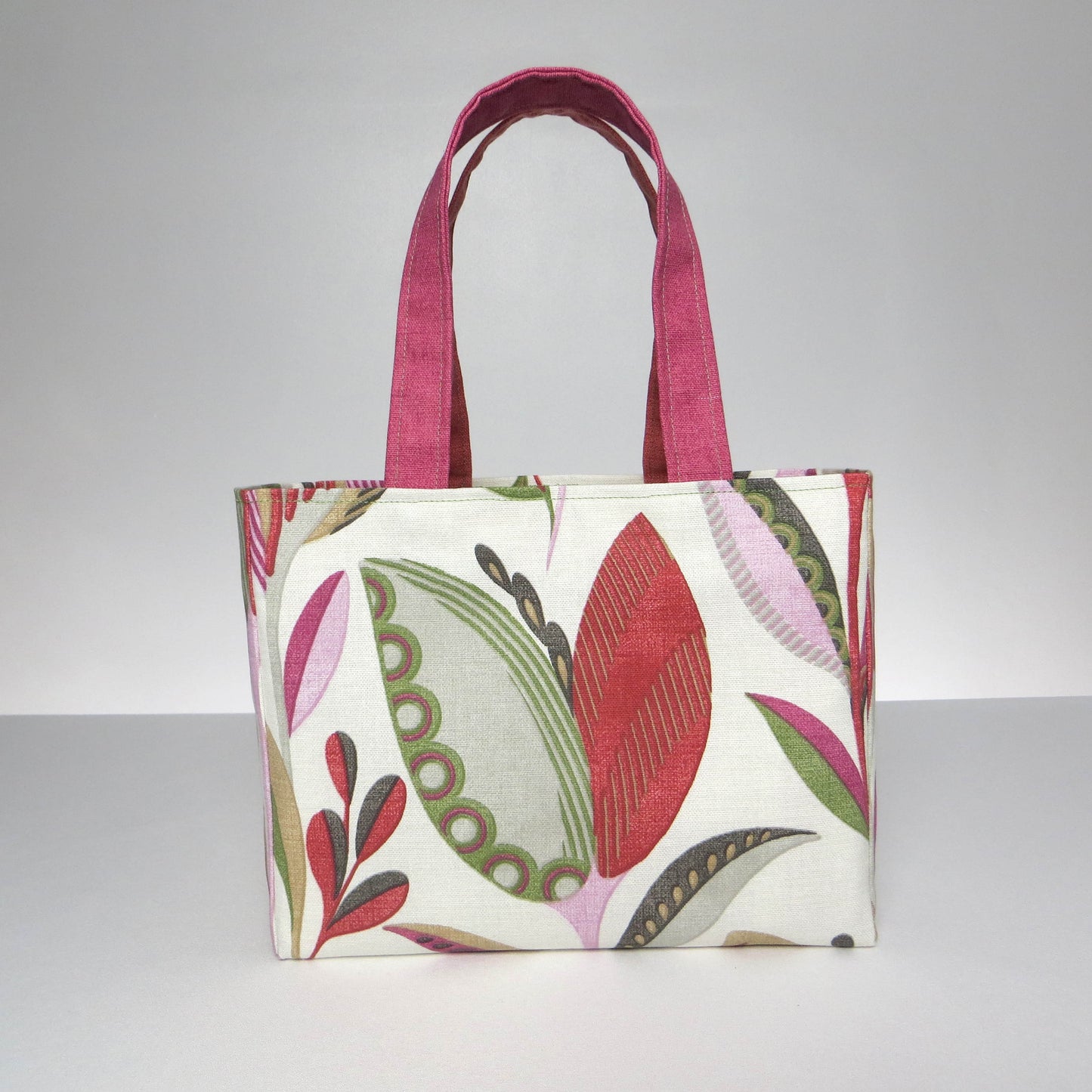 Small cotton tote bag with shades of moss green, raspberry pink, soft grey, and rhubarb red tulips on off-white background