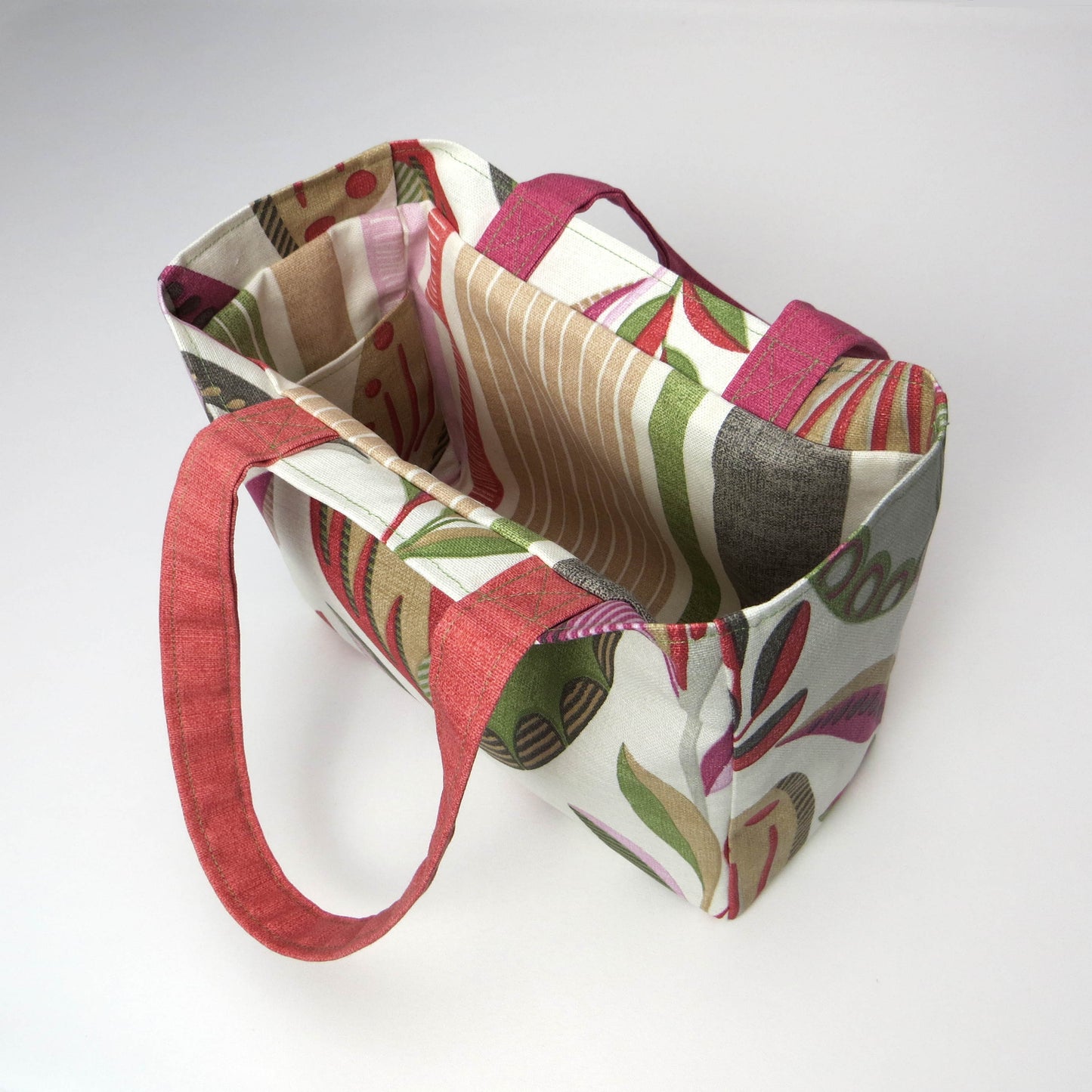 Small cotton tote bag with shades of moss green, raspberry pink, soft grey, and rhubarb red tulips on off-white background