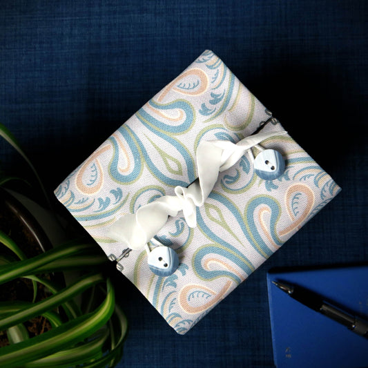 Square tissue box cover with charcoal grey and white flowers with blue, green and taupe Victorian embellishment on blue-grey background