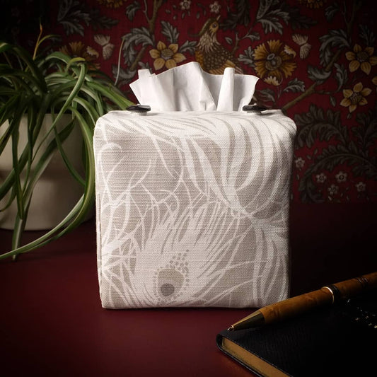 Square tissue box cover with white peacock feathers design on natural background