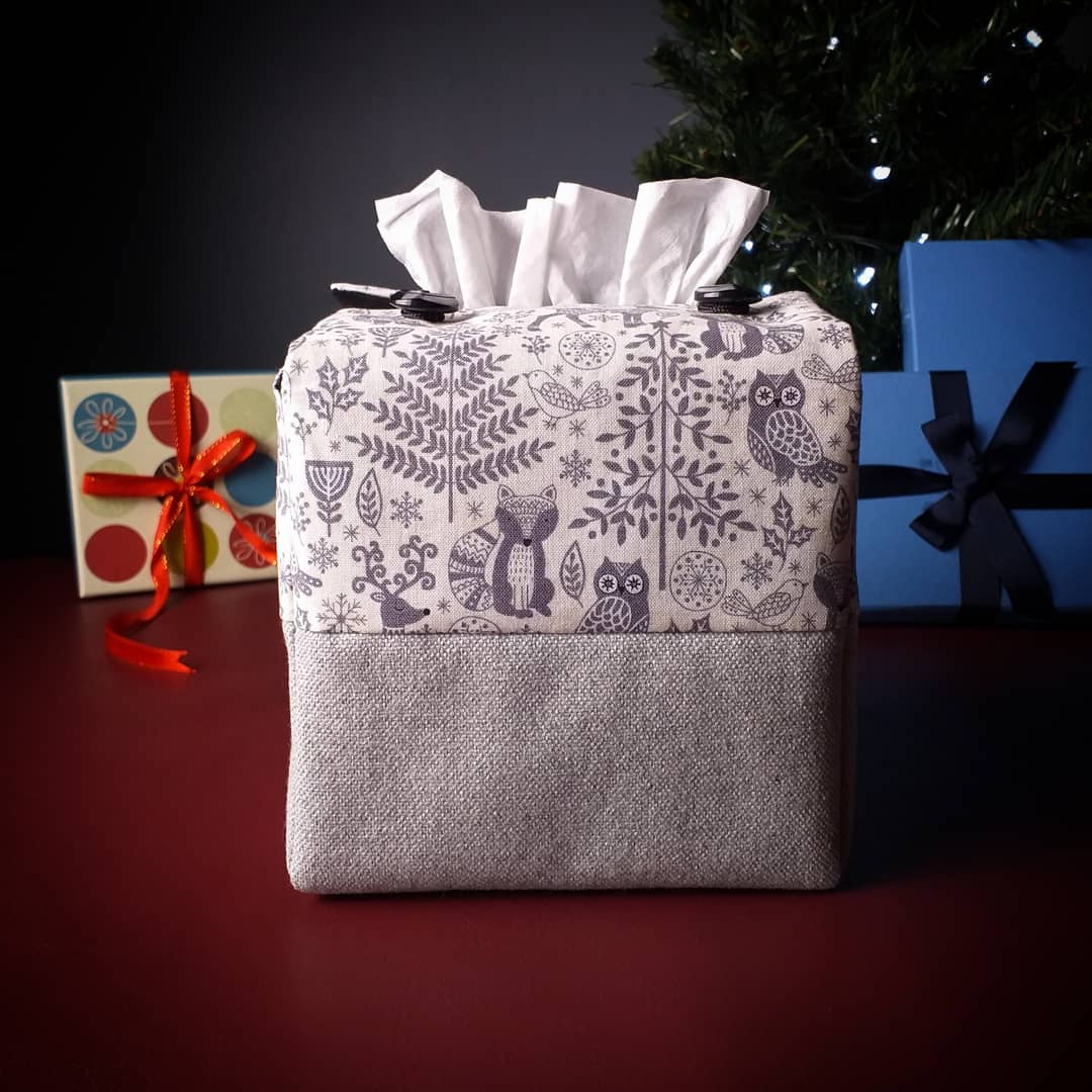 Square tissue box cover with Christmas themed winter forest scene on off-white background, and solid grey base