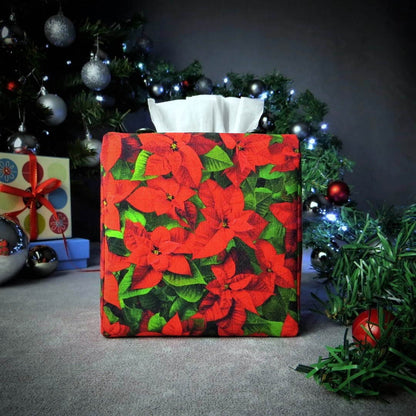 Square tissue box cover with holiday themed poinsettia design on green leaf pattern background