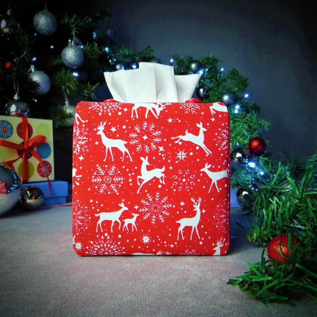 Square tissue box cover with holiday themed white reindeer design on red background