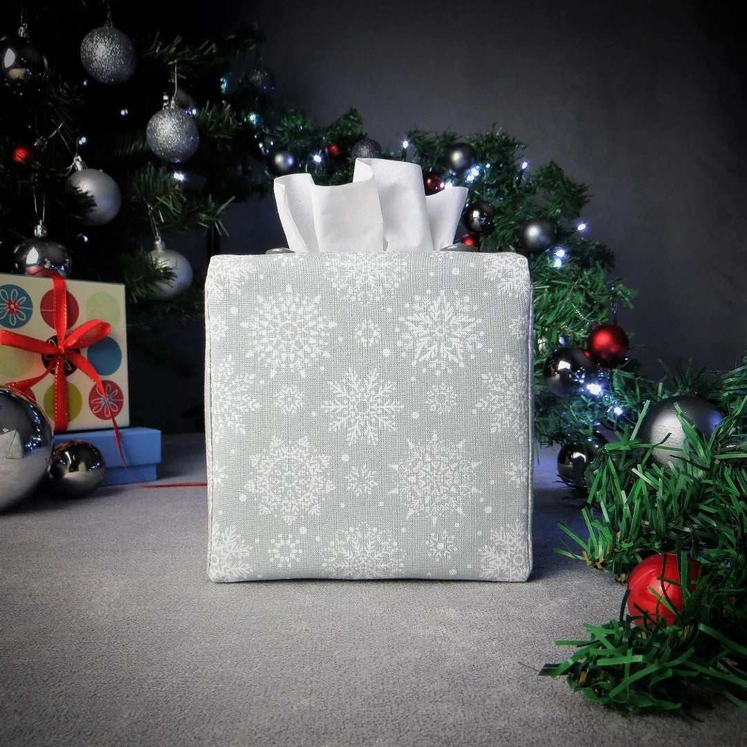 Square tissue box cover with winter themed white snowflakes design on grey background