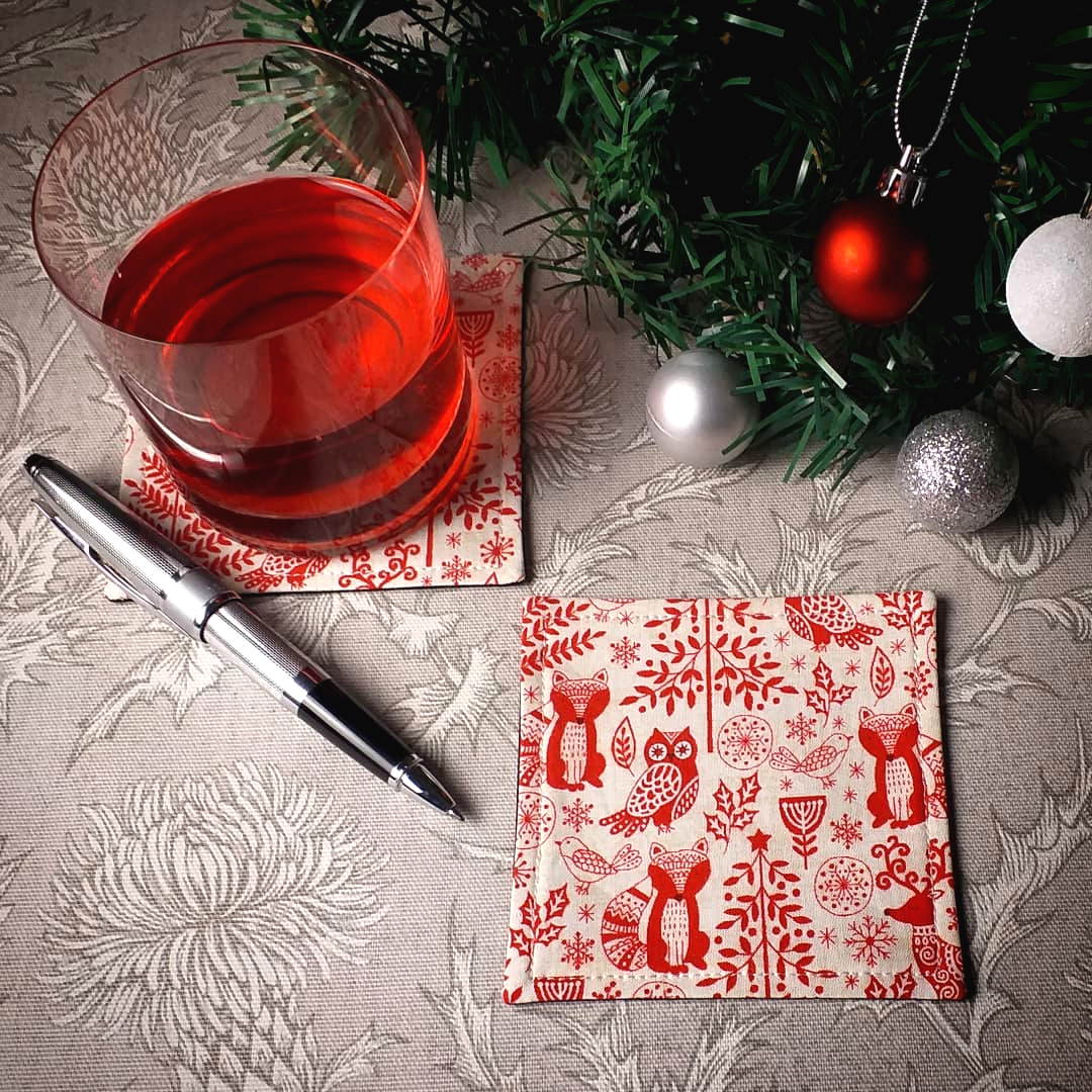 Square coasters with holiday themed winter forest scene on off-white background